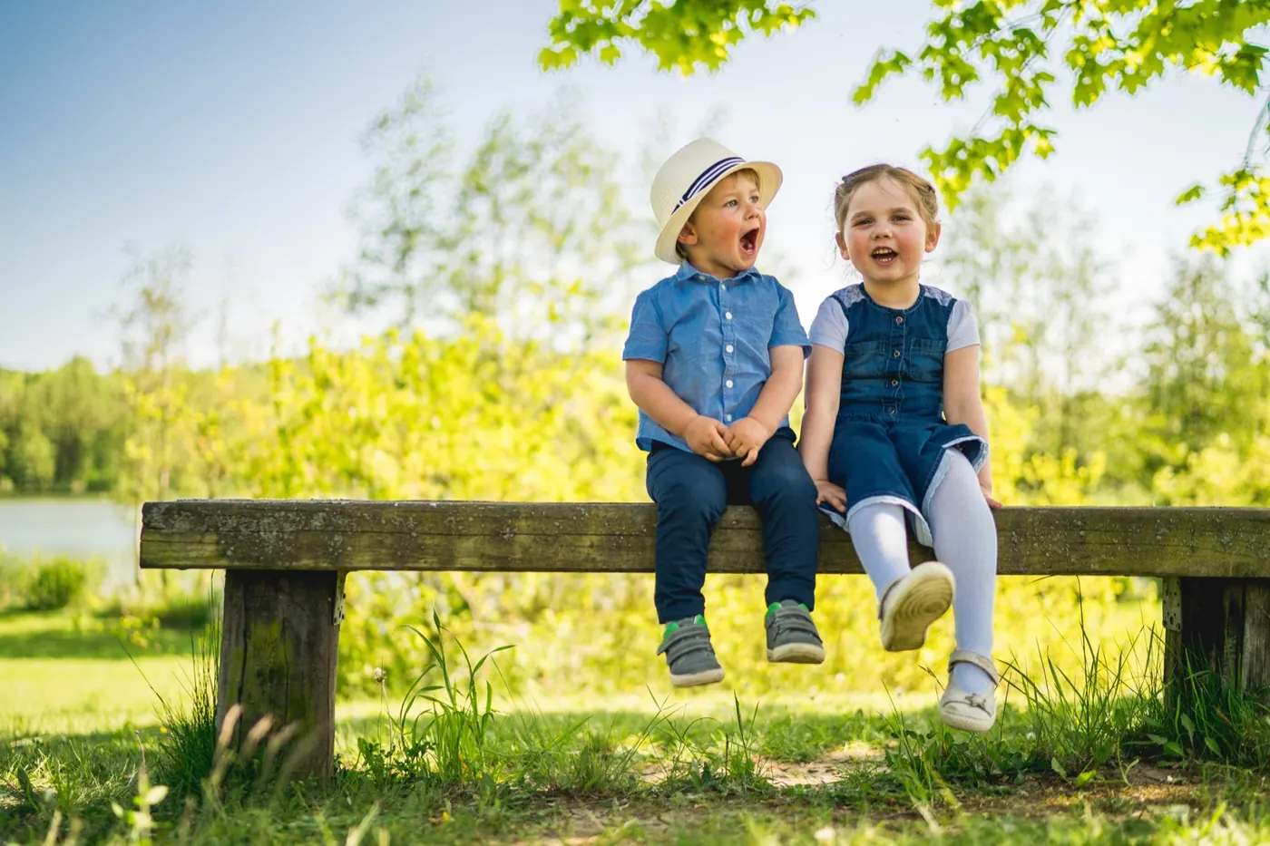 Zwei lachende Kinder auf einer Bank im Grünen