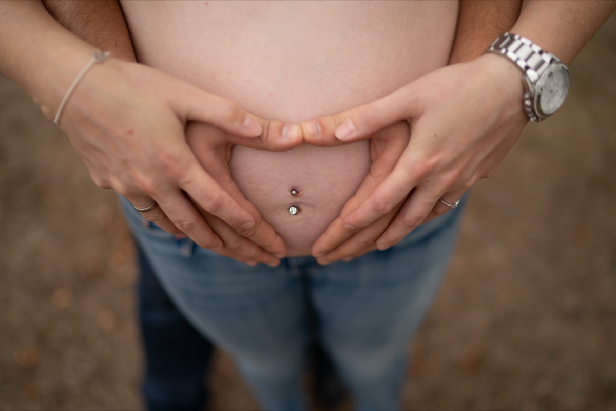 Babybauch-Fotoshooting – zwei Hände formen gemeinsam ein Herz über dem schwangeren Bauch