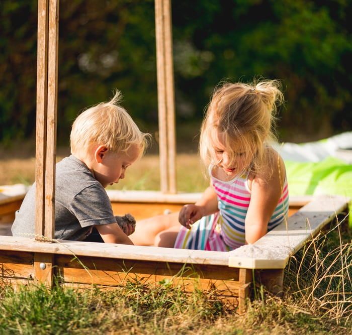 Kinderfotografie Osthessen – Geschwister spielen gemeinsam im Sandkasten bei Abendsonne