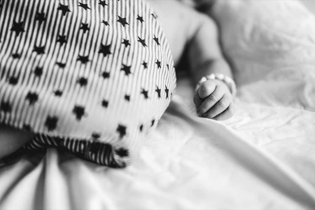 Neugeborenen-Shooting – winzige Babyfaust auf gestreiftem Strampler, zarte Schwarzweißaufnahme
