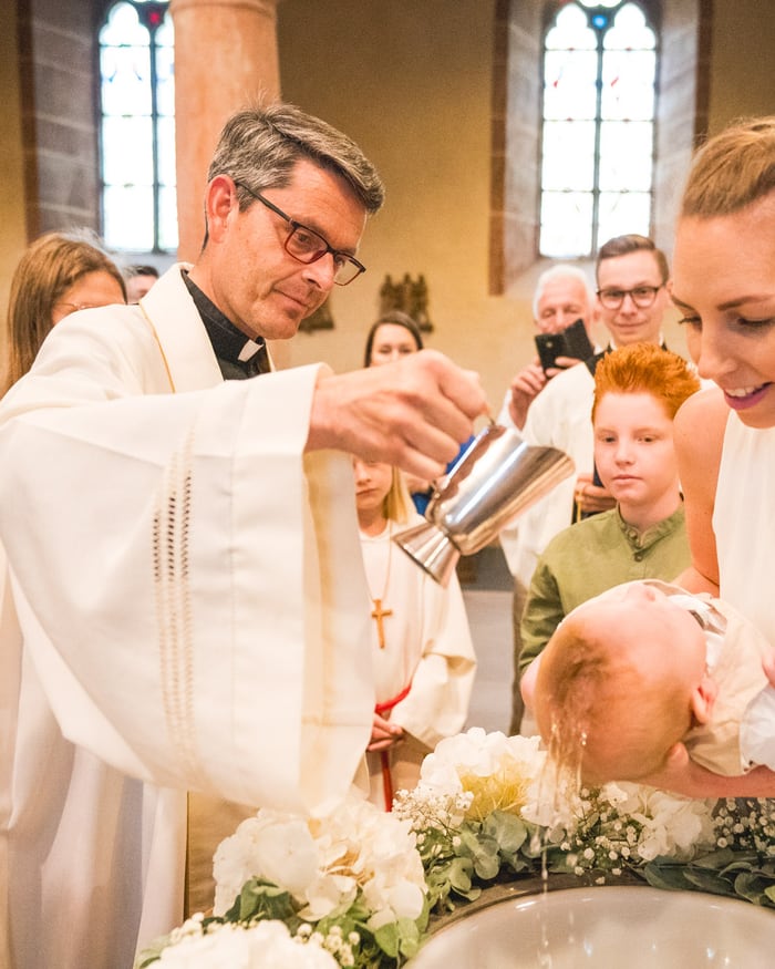 Taufe Fotografie Fulda – Priester tauft Baby in der Kirche, Mutter hält das Kind